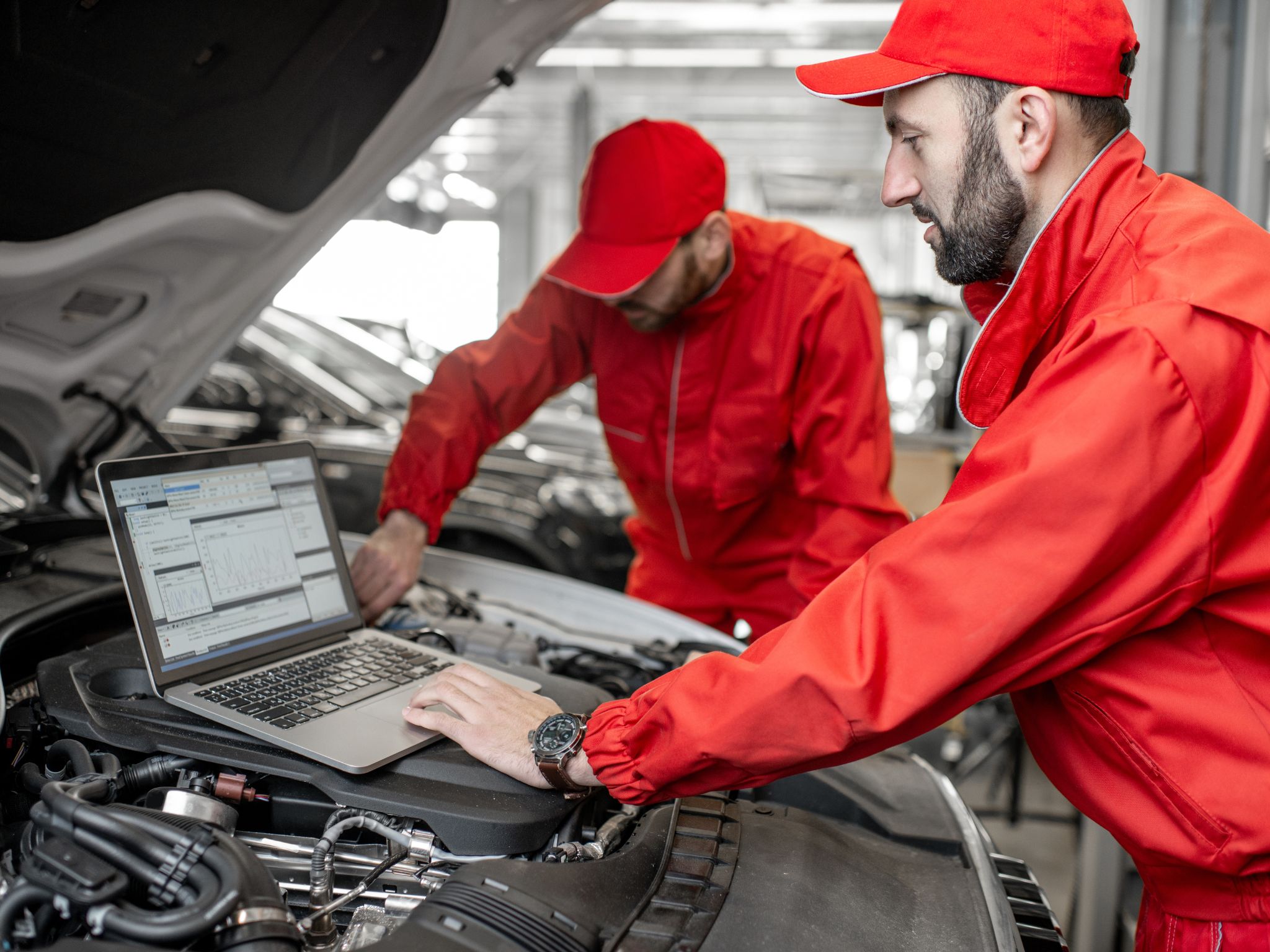 MOT test centre using computer whilst working on a vehicle